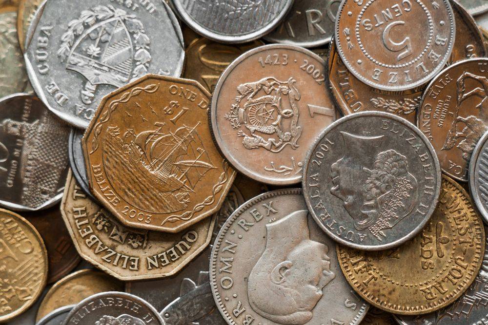 Aneka koin dari berbagai negara tersusun di atas meja sebagai ilustrasi cashback